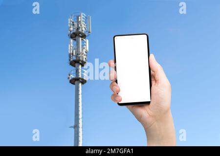 5G Kommunikationsturm mit Mann, der ein Smartphone benutzt Stockfoto