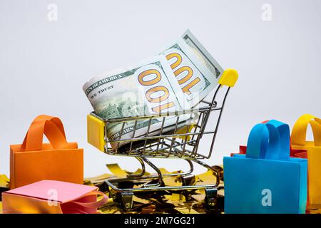 Einkaufstaschen und ein Wagen mit Geld auf weißem Hintergrund. Das Konzept des Verkaufs. Stockfoto