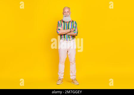 Portrait eines gutaussehenden optimistischen alten Mannes langer Bart tragen buntes Hemd Arme zusammengefaltet auf gelbem Hintergrund Stockfoto