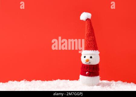 Weihnachtsmärchen-Komposition eines gestrickten Schneemanns mit Weihnachtsmann-Hut und -Pullover. Stockfoto