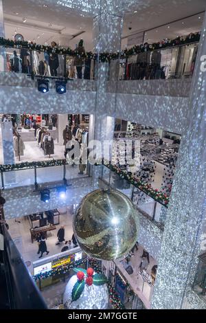 LONDON, Vereinigtes Königreich - 5. Dezember 2022: Selfridges in der Oxford Street. Weihnachtsdekoration. Goldene Discobälle, Rolltreppen. Stockfoto