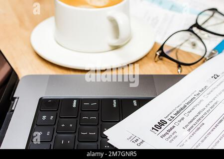 Laptop, Kaffee, Stift und US-Steuerformular auf dem Schreibtisch. Füllsteuern, selektiver Fokus Stockfoto