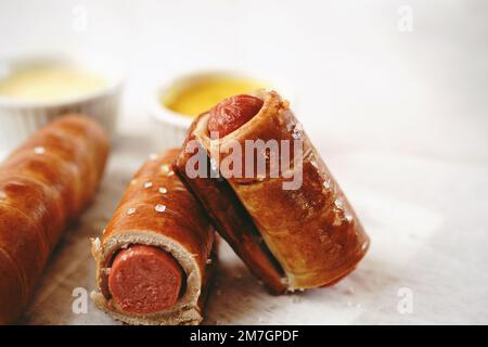 Brezel Hot Dogs serviert mit Sauce, selektiver Fokus - Snacks am Spieltag Stockfoto