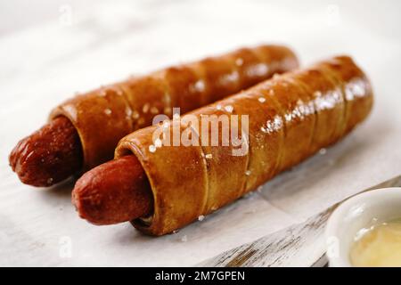 Brezel Hot Dogs serviert mit Sauce, selektiver Fokus - Snacks am Spieltag Stockfoto