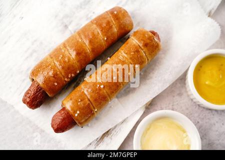 Brezel Hot Dogs serviert mit Sauce, selektiver Fokus - Snacks am Spieltag Stockfoto