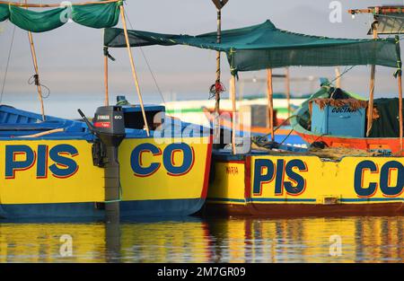 Gelbe Boote, registriert in Pisco, ankern vor dem Sandstrand in Paracas. Paracas, Ica, Peru. Stockfoto