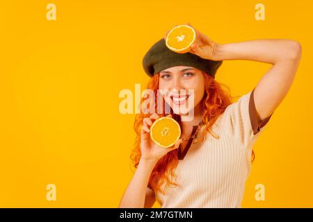 Teenager Rothaarige mit einer Orange auf isoliertem gelbem Hintergrund Stockfoto