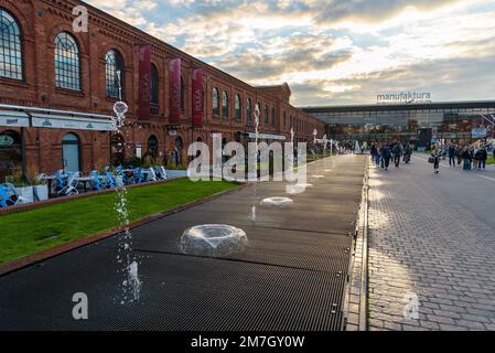 Lodz, Polen - 29. September 2022: Besucher besuchen den inneren Platz von Manufaktura bei Sonnenuntergang, ein Kunstzentrum, ein Einkaufszentrum und einen Freizeitkomplex Stockfoto