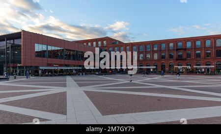 Lodz, Polen - 29. September 2022: Besucher besuchen den inneren Platz von Manufaktura bei Sonnenuntergang, ein Kunstzentrum, ein Einkaufszentrum und einen Freizeitkomplex Stockfoto