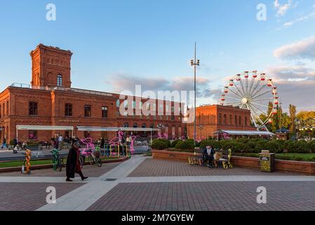 Lodz, Polen - 29. September 2022: Besucher besuchen den inneren Platz von Manufaktura bei Sonnenuntergang, ein Kunstzentrum, ein Einkaufszentrum und einen Freizeitkomplex Stockfoto