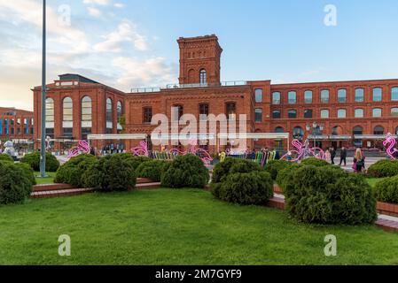 Lodz, Polen - 29. September 2022: Besucher besuchen den inneren Platz von Manufaktura bei Sonnenuntergang, ein Kunstzentrum, ein Einkaufszentrum und einen Freizeitkomplex Stockfoto