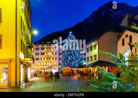 Nachtansicht der Brig Straße mit Weihnachtsbaum im Hintergrund der Alpen, Schweiz Stockfoto