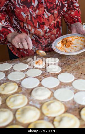 Nicht wiedererkennbare Frau, die traditionelle Knödel mit Thunfisch, gekochtem Ei und Tomatensoße füllt. Spanien Stockfoto