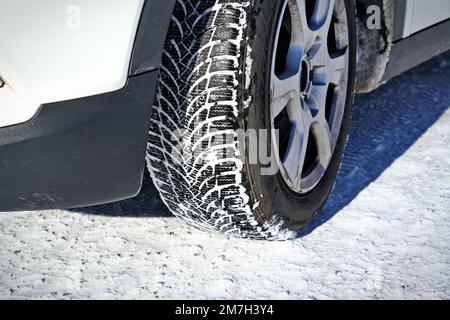 Auto mit Winterreifen auf Schneestraße fahren Stockfoto