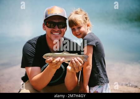 Mann und Mädchen mit einem Fisch, den sie im Bergteich gefangen haben Stockfoto