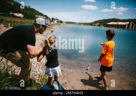 Die Familie fängt einen Fisch von einem Bergsee im Abenteuerurlaub Stockfoto