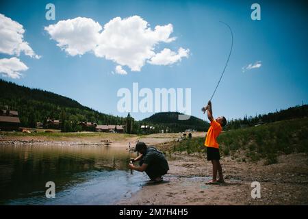 Der Junge fängt Fische vom See in den Bergen im Urlaub mit Dad Stockfoto