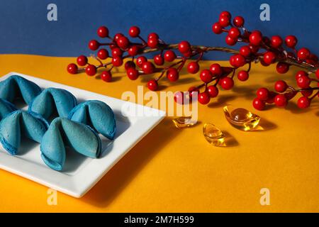Teller mit Glückskeksen und chinesischen Symbolen auf dem gelben Tisch, Nahaufnahme. Neujahrsfeier Stockfoto