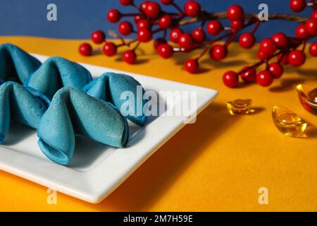Teller mit Glückskeksen und chinesischen Symbolen auf dem gelben Tisch, Nahaufnahme. Neujahrsfeier Stockfoto