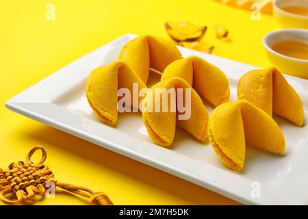 Teller mit Glückskeksen auf gelbem Hintergrund, Nahaufnahme. Chinesische Neujahrsfeier Stockfoto