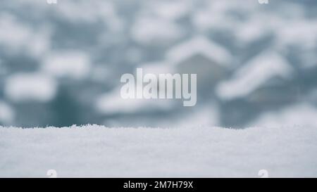 Hintergrundbild von herabfallendem Schnee. Herabfallende Schneeflocken im Hintergrund von Privathäusern. Schneewetter, Winter, Schneefall Stockfoto