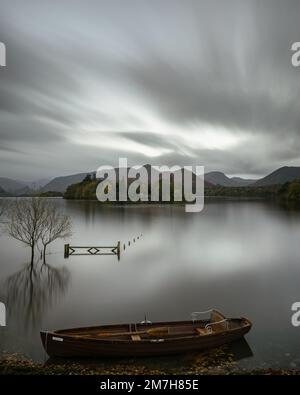 Langzeitaufnahme eines Ruderboots auf Derwentwater, Keswick, mit Tor, Derwent Isle und Cat Bells im Hintergrund und im See reflektiert Stockfoto