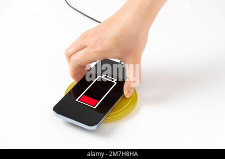 Nahaufnahme einer Frau, die ihr Smartphone auf weißem Hintergrund auflädt Stockfoto