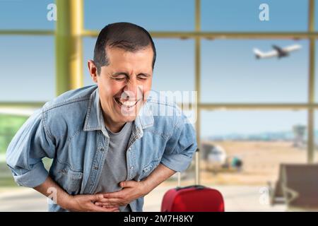 Ein hübscher, eleganter Mann am Flughafen, der lächelt und laut lacht, zu Last-Minute-Preisen. Fröhlicher Ausdruck Stockfoto