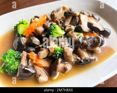 Gebratene Pilze mit Brokkoli-Karotten-Gemüse, Shiitake-Pilze mit Austernsauce kochen Essen auf weißem Teller, Shiitake-Pilze gekocht mit Fryi Stockfoto