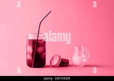 Ein Glas Eiskaffee in einem großen Glas mit Creme und Makronen in trendigen magentafarbenen Farben des Jahres 2023. Speisekonzept. Speicherplatz kopieren. Nahaufnahme. Stockfoto