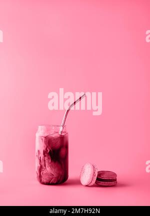 Ein Glas Eiskaffee in einem großen Glas mit Creme und Makronen in trendigen magentafarbenen Farben des Jahres 2023. Speisekonzept. Speicherplatz kopieren. Nahaufnahme. Stockfoto