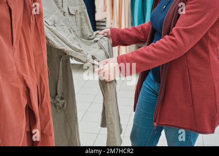 Eine weiße Schwangere im Laden kauft ein geräumiges Kleid in hellgrüner Farbe Stockfoto