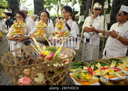 Frauen eines balinesischen Clans bringen spirituelle Opfer während einer Prozession mit, um die Geister ihrer verstorbenen Familienmitglieder zu ehren und zu reinigen, in einem Tempel in der Besakih-Tempelanlage, am Hang des Agung in Karangasem, Bali, Indonesien. Stockfoto