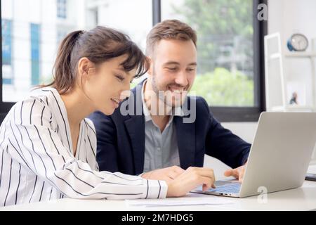 Der junge kaukasische Geschäftsmann bildet eine Unternehmerin aus, die im Büro selbstbewusst zusammenarbeitet, Manager und Mitarbeiter diskutieren und mit LAP arbeiten Stockfoto