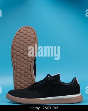 Moderne, trendige schwarze Paar Sneakerschuhe mit blauem Studiohintergrund Stockfoto
