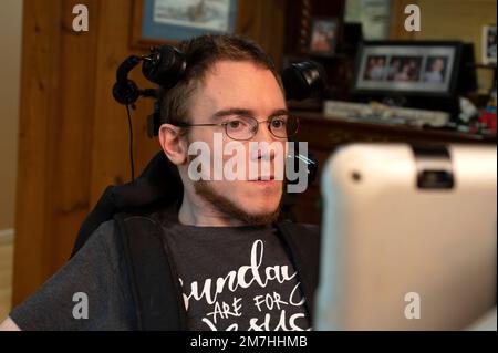 Valle Crusis, North Carolina, USA. 12. September 2022. Luke Wilcox, 22, sitzt im Rollstuhl im Landhaus seiner Eltern, um fernzusehen und auf seinem speziellen Computer zu tippen, der seinen Augenblick erkennt, um seine Nachrichten zu tippen. (Kreditbild: © Robin Rayne/ZUMA Press Wire) NUR REDAKTIONELLE VERWENDUNG! Nicht für den kommerziellen GEBRAUCH! Stockfoto