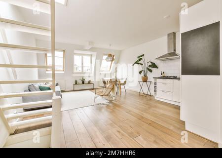 Ein Wohnzimmer mit Holzfußboden und weißen Wänden an der Wand, es gibt eine offene Treppe, die in die zweite Etage führt Stockfoto