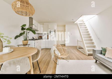 Ein Wohnzimmer mit weißen Wänden und Holzfußboden in der Mitte des Zimmers ist eine offene Treppe, die zur zweiten führt Stockfoto