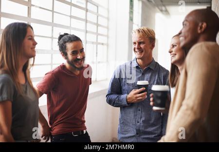 Gespräche mit Kollegen während der Arbeit. Eine vielfältige Gruppe von Freunden in einem Flur. Stockfoto