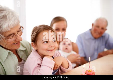 Ich wünsche mir ein Pony. Porträt einer glücklichen dreigenerationalen Familie, die zu Hause Geburtstag feiert. Stockfoto