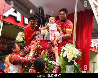 Manila, Philippinen. 09. Januar 2023. Die Mitglieder von Hijos Del Nazareno helfen sich gegenseitig, ein 7 Monate altes Baby zu heben, um mit der Nachbildung des Schwarzen Nazarenen gesegnet zu werden. Nach zwei Jahren der Beschränkungen der COVID-19-Pandemie können nun katholische Anhänger an der ersten großen Feier des Fests der Schwarzen Nazarener teilnehmen. Hunderttausende Anhänger tauchten in der Quiapo Kirche und anderen wichtigen Straßen in Manila auf, um ihre Hingabe für die Nachbildung des dunkelhäutigen Jesus Christus aus dem 17. Jahrhundert zu zeigen. Kredit: SOPA Images Limited/Alamy Live News Stockfoto