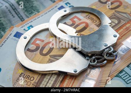 Handschellen vor dem Hintergrund von 50 Euro. Finanzkriminalität, schmutziges Geld und Korruptionskonzept. Stockfoto