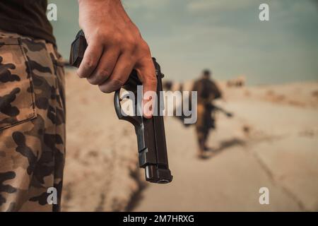 Polizist, ein Soldat der Spezialeinheit, getarnt, mit einer schwarzen halbautomatischen Pistole, die er in seinen Händen hält. Stockfoto