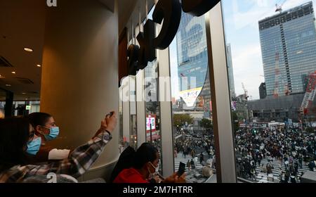 Touristen genießen den Blick auf die Shibuya Crossing vom Starbucks Coffee Shop in Shibuya, Tokio, Japan. Stockfoto