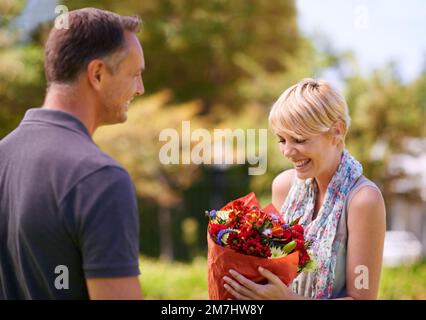 Danke, sie sind wunderschön. Eine reife Frau, die Blumen von ihrem Mann bekommt. Stockfoto