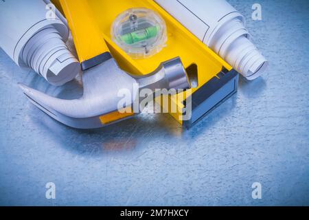 Nahaufnahme von gerollten Bauplänen auf Bauhöhe Klauenhammer auf metallischem Hintergrund Baukonzept. Stockfoto