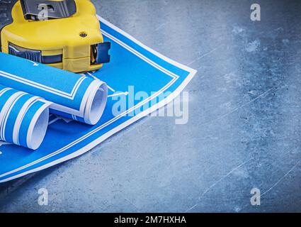 Zusammensetzung von blauen Blaupausen-Maßband auf zerkratztem metallischem Hintergrund. Stockfoto
