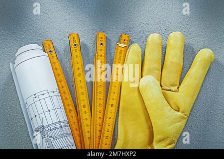 Zusammensetzung von Arbeitshandschuhen Baupläne Holzmeter auf Betonhintergrund Baukonzept. Stockfoto