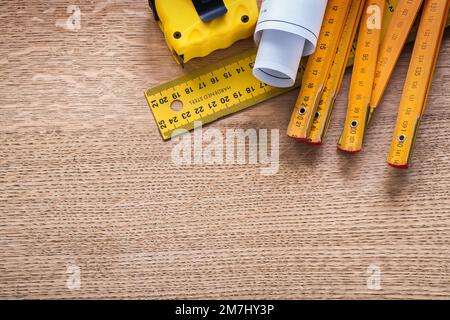 Baupläne und Messinstrumente auf Eichenholzplatten-Wartungskonzept Stockfoto