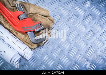 Rohrzange Blueprints Lederschutzhandschuhe auf kanalisiertem Metallhintergrund Baukonzept. Stockfoto